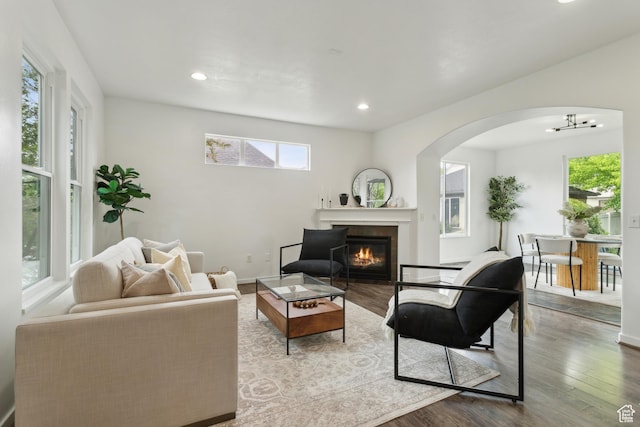 11572 S Harvest Rain Ave, South Jordan, UT 84009 - living room featuring arched walkways, recessed lighting, a glass covered fireplace, wood finished floors, and a chandelier