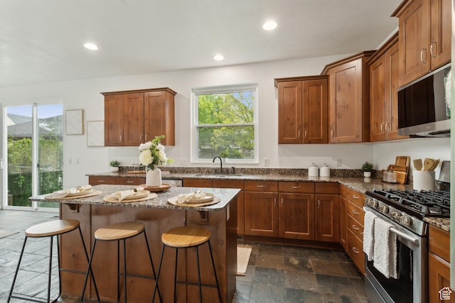 11572 S Harvest Rain Ave, South Jordan, UT 84009 - kitchen with stainless steel appliances, a sink, stone tile flooring, a breakfast bar area, and dark stone countertops