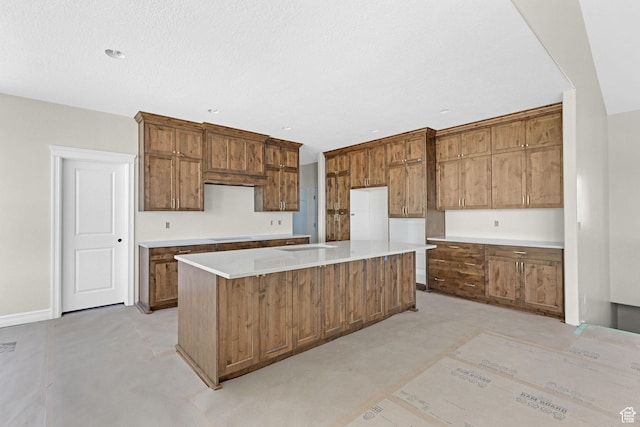2881 N 3475 W Unit 17, Plain City, UT 84404 - kitchen featuring a kitchen island, brown cabinets, baseboards, and light countertops