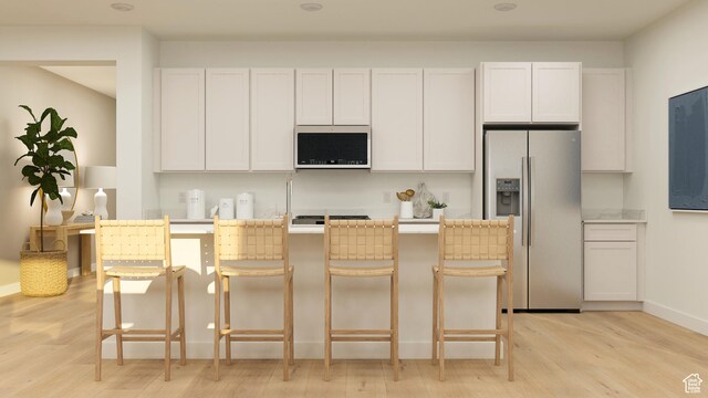 590 S Cecita Way, St George, UT 84770 - kitchen with white cabinetry, appliances with stainless steel finishes, a kitchen bar, and light wood-type flooring