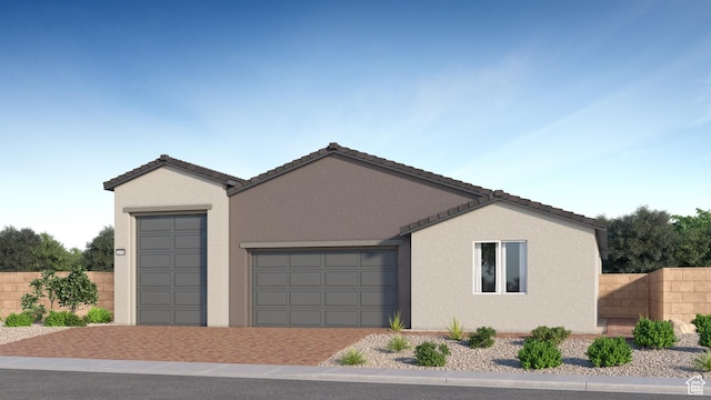 view of front of property with an attached garage, decorative driveway, fence, and stucco siding