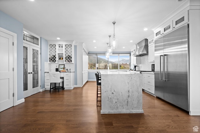 1235 E 200th St S Unit 1001, Salt Lake City, UT 84102 - kitchen featuring wall chimney range hood, white cabinets, a breakfast bar area, backsplash, and stainless steel built in refrigerator