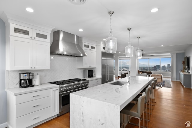 1235 E 200th St S Unit 1001, Salt Lake City, UT 84102 - kitchen featuring decorative backsplash, a kitchen island with sink, high end appliances, a sink, and wall chimney exhaust hood