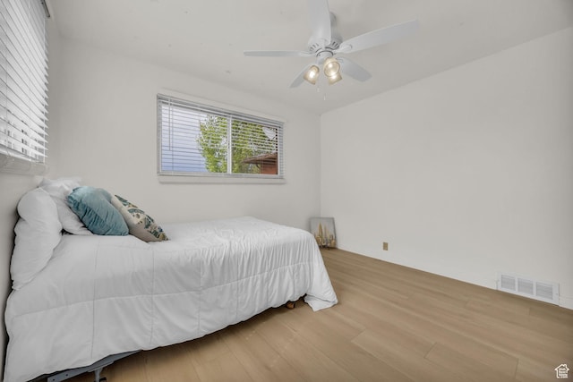 bedroom with a ceiling fan, visible vents, and wood finished floors