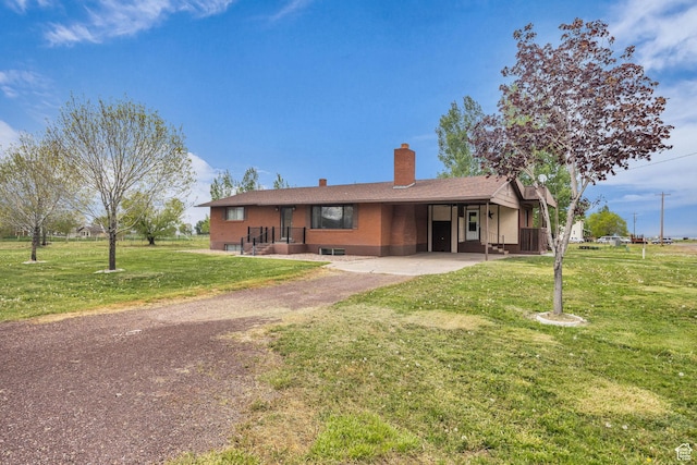 single story home with a front lawn, aphalt driveway, a chimney, and a carport