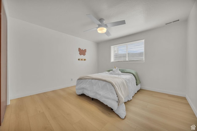 bedroom featuring ceiling fan, baseboards, visible vents, and light wood-style flooring