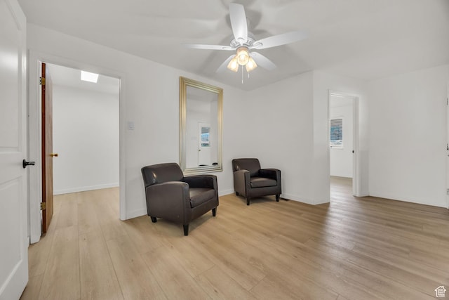 sitting room featuring ceiling fan, baseboards, and light wood-type flooring