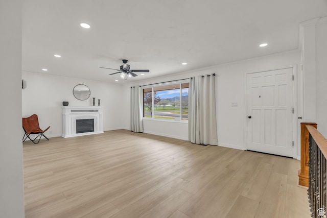 unfurnished living room with a glass covered fireplace, ceiling fan, light wood-style floors, and recessed lighting