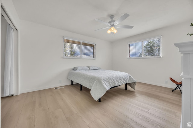 bedroom featuring a closet, baseboards, ceiling fan, and light wood-style floors