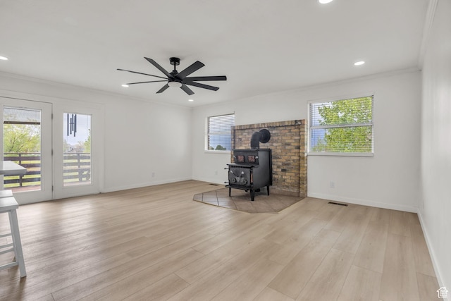 living room with plenty of natural light, a wood stove, crown molding, and visible vents
