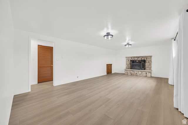 unfurnished living room with light wood-style floors and a stone fireplace