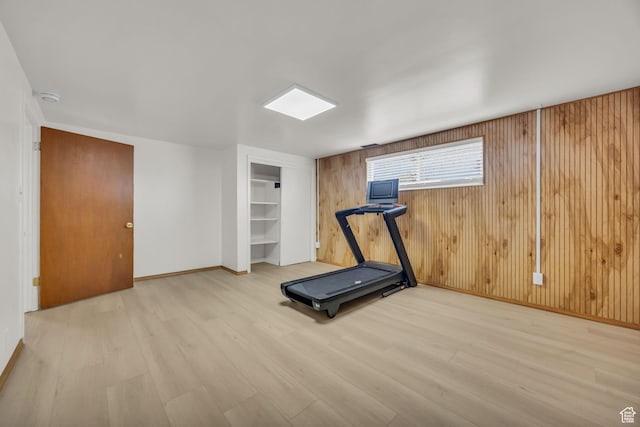 workout room featuring baseboards, wood walls, built in features, and wood finished floors
