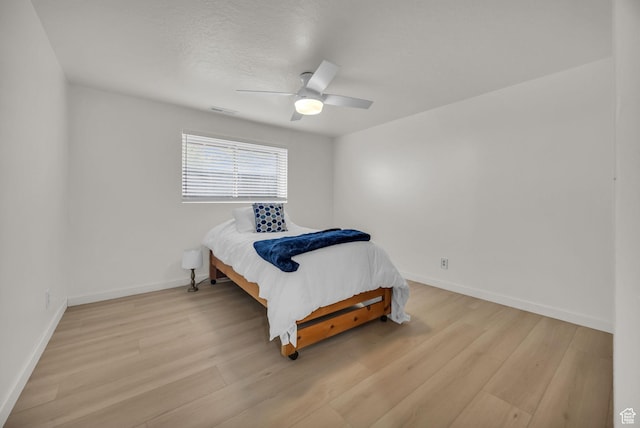bedroom featuring baseboards, visible vents, ceiling fan, and light wood finished floors