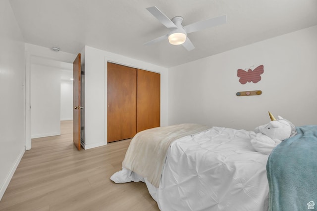 bedroom featuring a closet, light wood-style flooring, ceiling fan, and baseboards