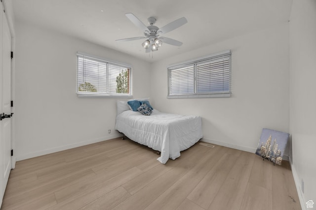 bedroom with light wood-style floors, baseboards, and ceiling fan