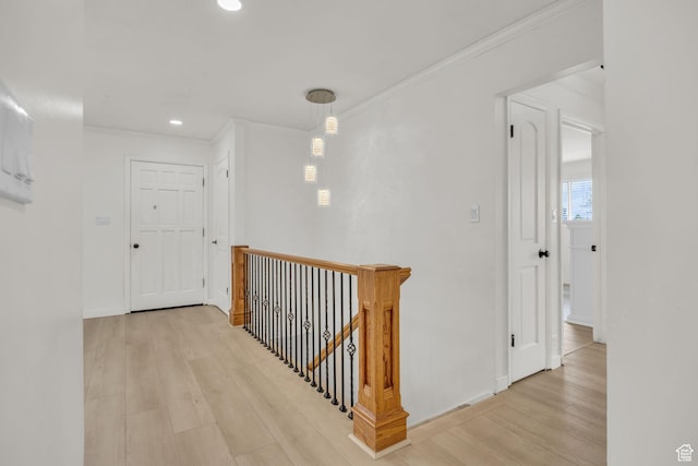 hallway with ornamental molding, wood finished floors, baseboards, recessed lighting, and an upstairs landing