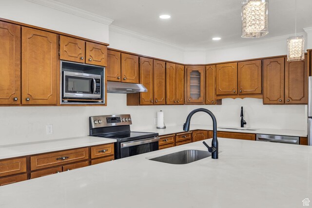 kitchen with a sink, appliances with stainless steel finishes, brown cabinetry, and under cabinet range hood