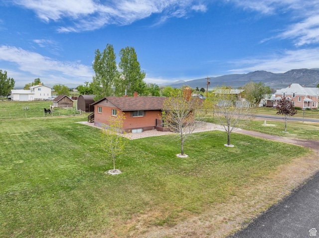 view of front of property with a chimney, a mountain view, and a front yard