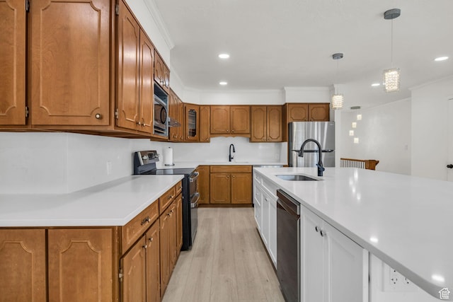 kitchen with a sink, appliances with stainless steel finishes, brown cabinetry, and light wood finished floors