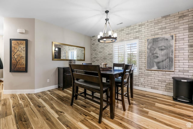 5764 Greenwich Cir, Stansbury Park, UT 84074 - dining room with brick wall, visible vents, wood finished floors, baseboards, and a chandelier