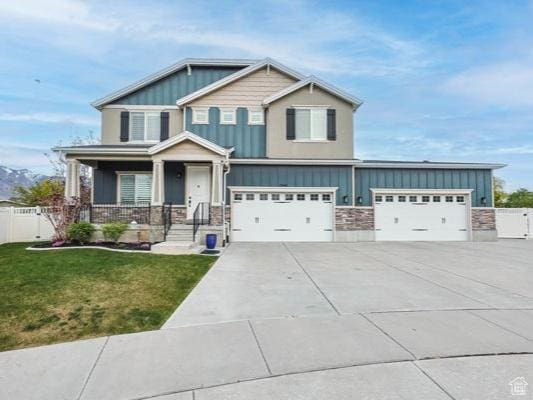 craftsman house with board and batten siding, fence, driveway, and a front yard