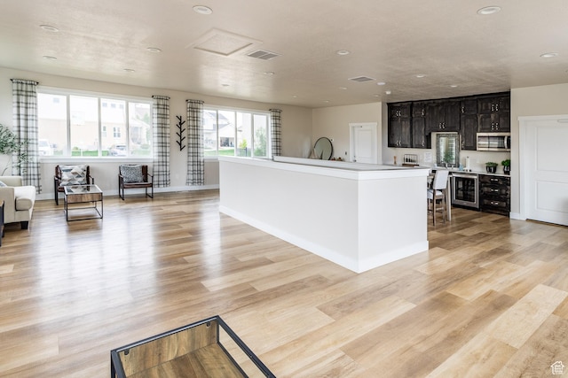 940 N 90 W, Santaquin, UT 84655 - kitchen with stainless steel microwave, open floor plan, light wood-type flooring, an island with sink, and recessed lighting