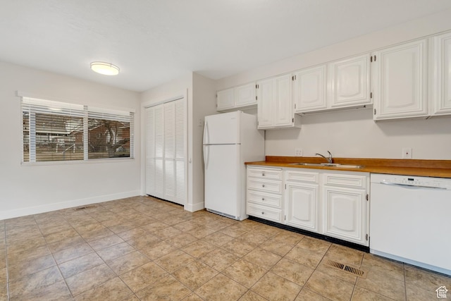 kitchen featuring white cabinets, a sink, white appliances, baseboards, and visible vents