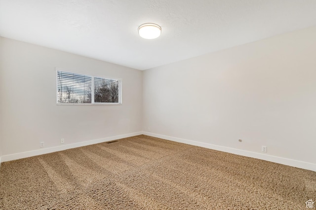 spare room featuring baseboards, carpet floors, and visible vents