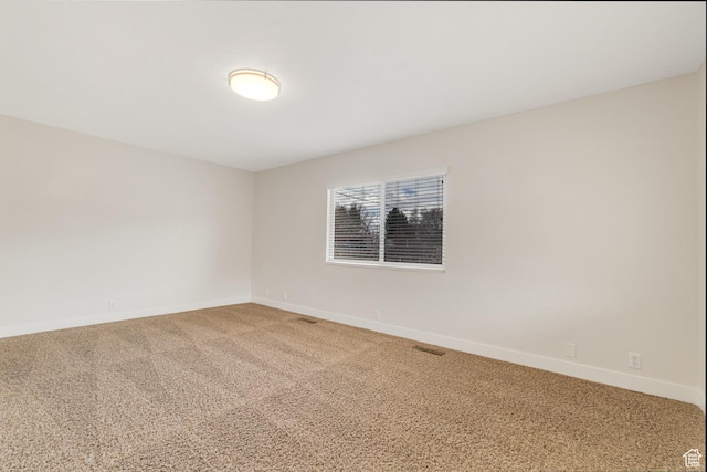spare room featuring baseboards and light carpet