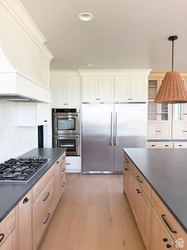 302 W Horizon View Loop Unit 35, Elk Ridge, UT 84651 - kitchen with backsplash, appliances with stainless steel finishes, hanging light fixtures, light wood-type flooring, and custom exhaust hood