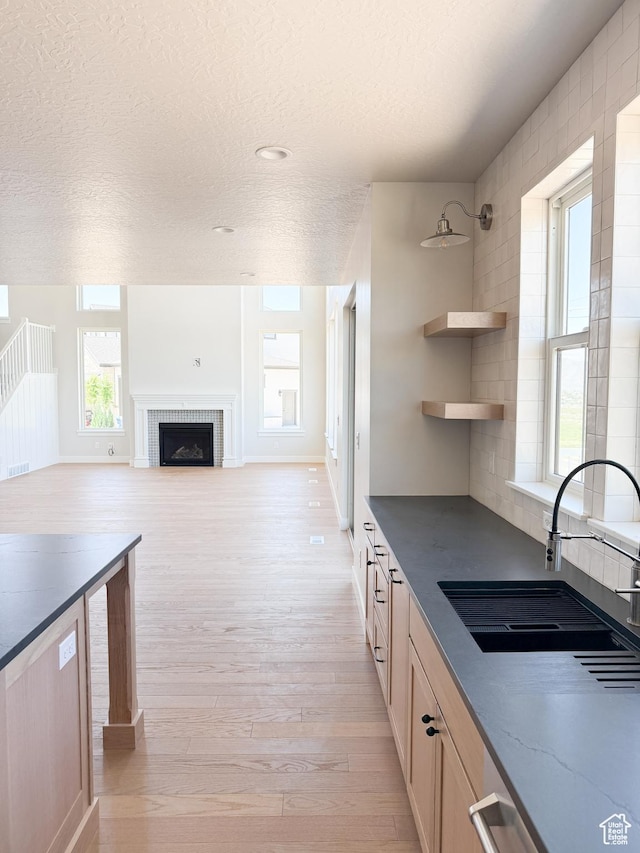 302 W Horizon View Loop Unit 35, Elk Ridge, UT 84651 - kitchen featuring a sink, a fireplace, a textured ceiling, light wood-type flooring, and visible vents
