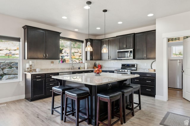 4852 N Arctic Fox Cir W Unit 2800, Lehi, UT 84043 - kitchen featuring a breakfast bar area, a center island, tasteful backsplash, light stone counters, and stainless steel appliances