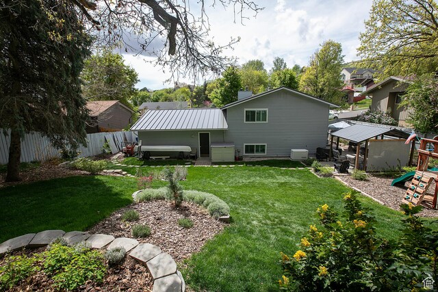 5716 S Maplewood Dr E, South Ogden, UT 84405 - back of property with fence, a playground, metal roof, a gazebo, and a yard