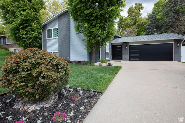 mid-century inspired home with a standing seam roof, a garage, brick siding, a front lawn, and concrete driveway