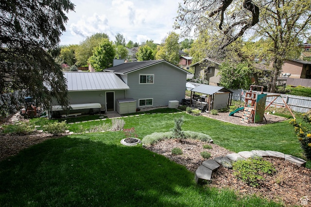 5716 S Maplewood Dr E, South Ogden, UT 84405 - back of property with a fenced backyard, a playground, a yard, and metal roof