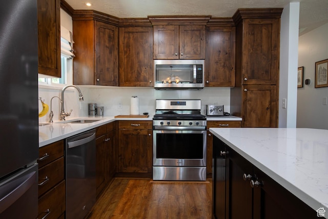 5716 S Maplewood Dr E, South Ogden, UT 84405 - kitchen with dark brown cabinets, light stone countertops, a sink, dark wood finished floors, and appliances with stainless steel finishes