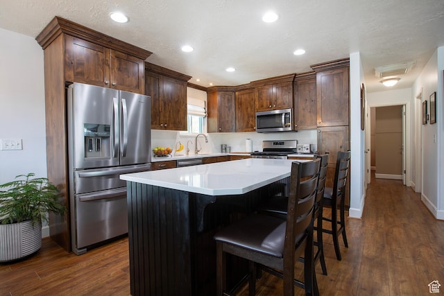 5716 S Maplewood Dr E, South Ogden, UT 84405 - kitchen featuring a kitchen island, appliances with stainless steel finishes, dark wood-style floors, and a breakfast bar