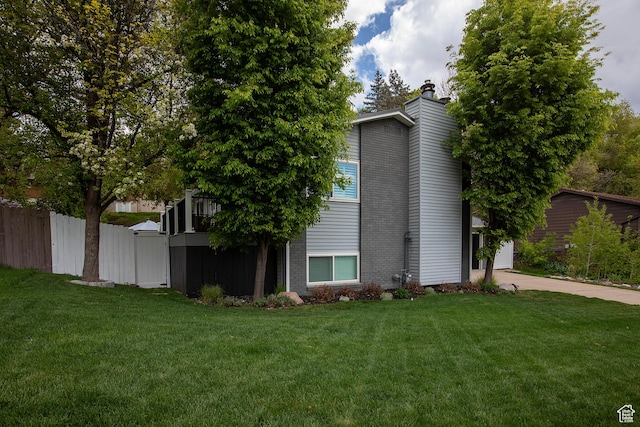 5716 S Maplewood Dr E, South Ogden, UT 84405 - view of side of property with fence, concrete driveway, a chimney, and a lawn