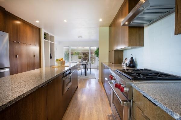 2812 E Commonwealth Ave S, Salt Lake City, UT 84109 - kitchen featuring stone countertops, modern cabinets, range hood, light wood-type flooring, and appliances with stainless steel finishes
