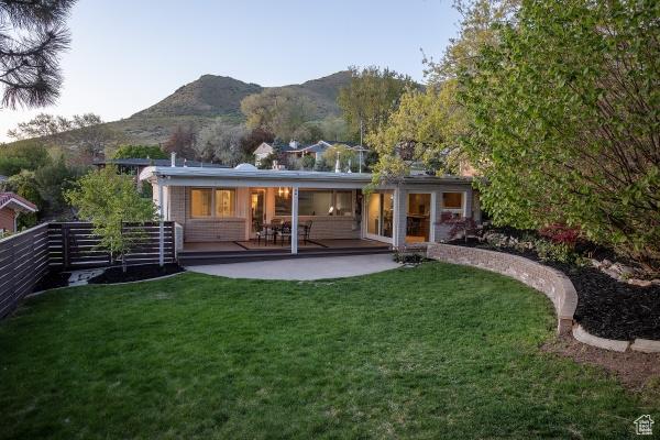2812 E Commonwealth Ave S, Salt Lake City, UT 84109 - rear view of house featuring a lawn, fence, a mountain view, and a patio area