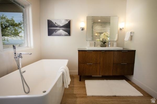 2812 E Commonwealth Ave S, Salt Lake City, UT 84109 - full bathroom with double vanity, a freestanding bath, wood finished floors, a sink, and baseboards