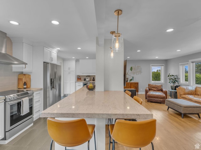 3133 S 2700 E, Millcreek, UT 84109 - kitchen with wall chimney range hood, open floor plan, stainless steel appliances, recessed lighting, and white cabinetry