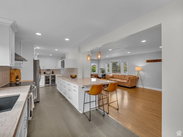 3133 S 2700 E, Millcreek, UT 84109 - kitchen featuring under cabinet range hood, stainless steel appliances, a breakfast bar area, and tasteful backsplash