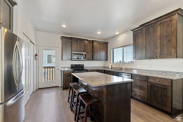 2242 S Beachcomber Ln, Garden City, UT 84028 - kitchen with dark brown cabinetry, light wood-style floors, a center island, a sink, and appliances with stainless steel finishes