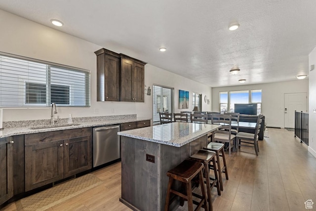 2242 S Beachcomber Ln, Garden City, UT 84028 - kitchen featuring stainless steel dishwasher, a kitchen island, dark brown cabinets, a kitchen bar, and a sink