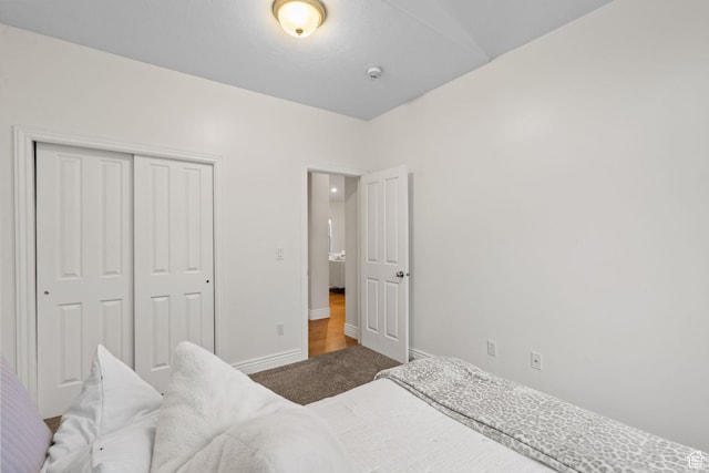 carpeted bedroom with a closet and baseboards