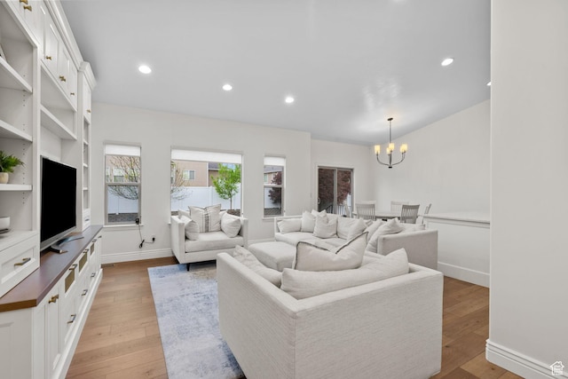 living room with recessed lighting, a notable chandelier, and light wood-style floors