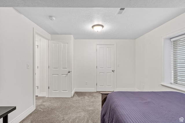bedroom featuring a textured ceiling, visible vents, baseboards, and carpet