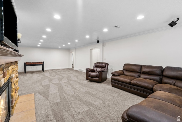 living area with arched walkways, a stone fireplace, recessed lighting, visible vents, and ornamental molding