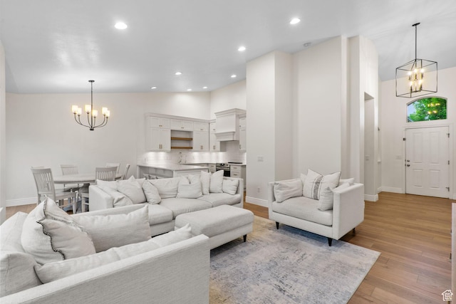 living room with a notable chandelier, high vaulted ceiling, recessed lighting, baseboards, and light wood-type flooring